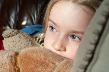 Close up of pretty young blonde girl's eyes while cuddling her teddy