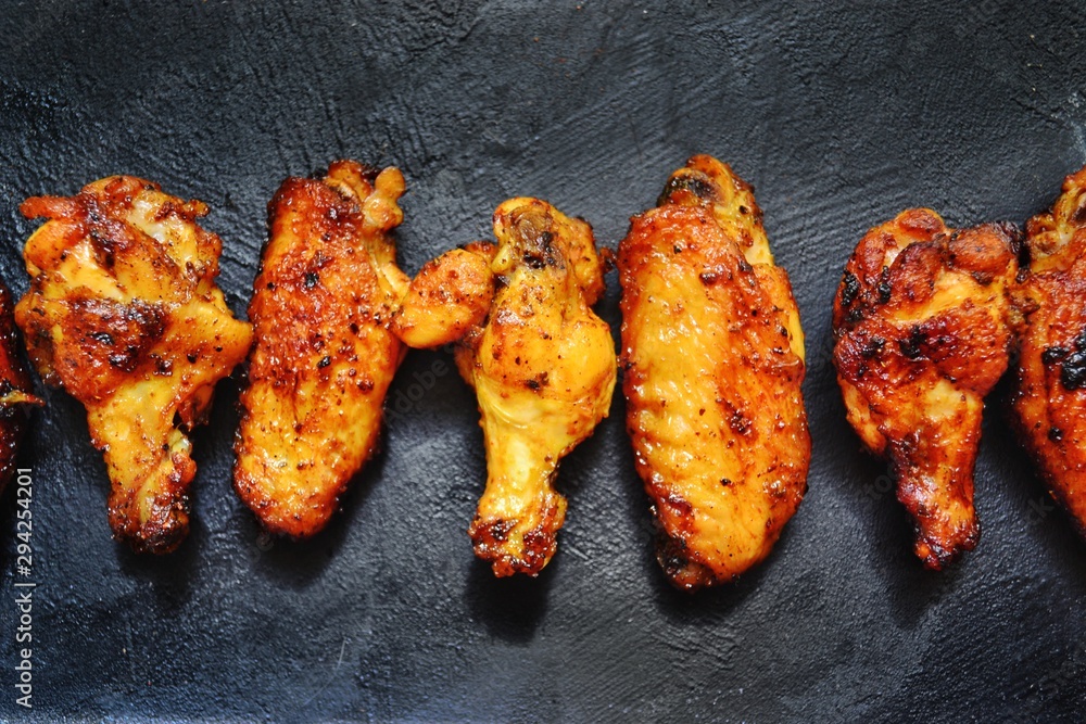 Wall mural fried chicken wings. chicken wings on a dark background on a blackboard. barbecue meat, grill. sauce