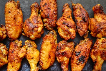 Fried chicken wings. Chicken wings on a dark background on a blackboard. Barbecue meat, grill. Sauce in bowls, ketchup, mayonnaise, mustard, cheese sauce. Appetizing fried meat. Place for your text