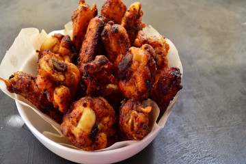 Fried chicken wings. Chicken wings on a dark background. Barbecue meat, grill. Sauce in bowls, ketchup, mayonnaise, mustard, cheese sauce. Appetizing fried meat in the white plate. bowl.