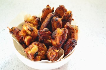 Appetizing chicken wings in a white bowl. Grilled chicken wings on a white background.