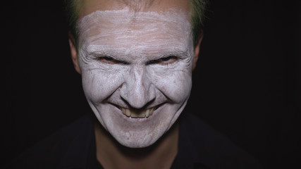 Clown Halloween man portrait. Close-up of an evil clowns face. White face makeup