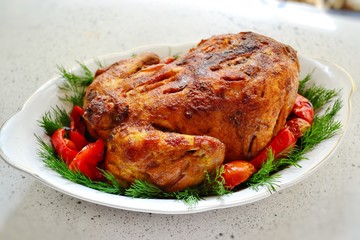 Baked whole chicken.  Appetizing whole chicken in the white plate on a dark concrete table background. Festive, Christmas dish.