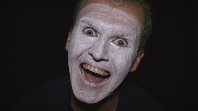 Clown Halloween man portrait. Close-up of an evil clowns face. White face makeup