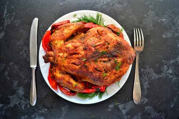 Baked whole chicken.  Appetizing whole chicken in the white plate on a dark concrete table background. Festive, Christmas dish.