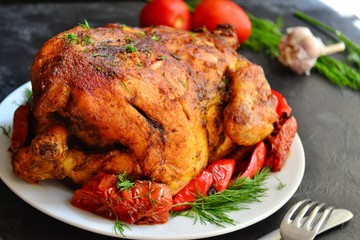 Baked whole chicken.  Appetizing whole chicken in the white plate on a dark concrete table background. Festive, Christmas dish.