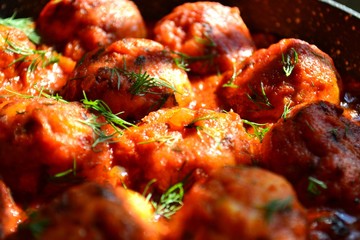Meatballs in tomato sauce, colse up. Appetizing chicken meatballs on a dark table background.