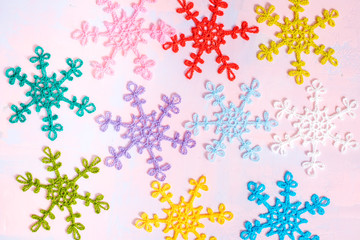 Crocheted multi-colored snowflakes. Crocheted doily. Handmade creativity. Bright christmas card on pink and purple background. Flat lay,top view, copy space.