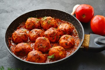 Meatballs in tomato sauce. Chicken meatballs. Meatballs in a pan on a dark table background isolated.