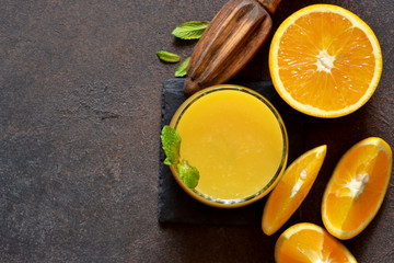 Orange juice, oranges and and juicer on stone background. Top view with copy space