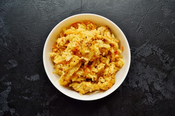 Rice in a white bowl. Rice dish on a dark table background. Pilaf, rice porridge, cooked rice with vegetables. Healthy vegetarian food.