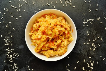 Rice in a white bowl. Rice dish on a dark table background. Pilaf, rice porridge, cooked rice with vegetables. Healthy vegetarian food.