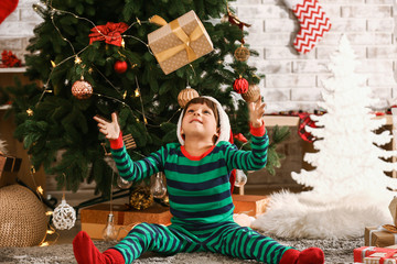 Cute little boy throwing Christmas gift at home