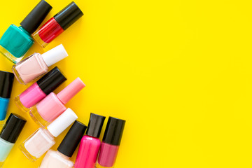 Set of colorful nail polish. Polish bottels on yellow background top view copy space