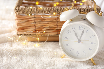 Alarm clock with glowing garland on plaid