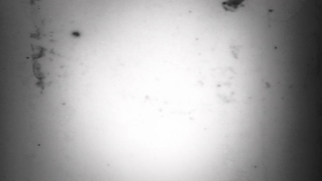 Flicker 118: A punch-hole and writing on dusty film leader (Loop).