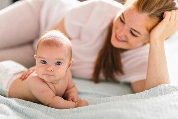 Mom hugs with her newborn baby in bed. Four month old baby. Baby care, tenderness, motherhood