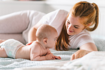 Mom hugs with her newborn baby in bed. Four month old baby. Baby care, tenderness, motherhood