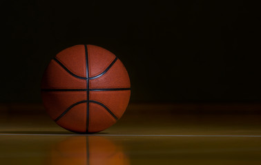 Basketball On Hardwood Court Floor With Spot Lighting