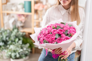 Lots of buds Roses of pink fuchsia color. Bouquet in woman hand. the work of the florist at a...