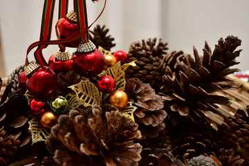 cascabeles rojos sostenidos sobre frutos de pino