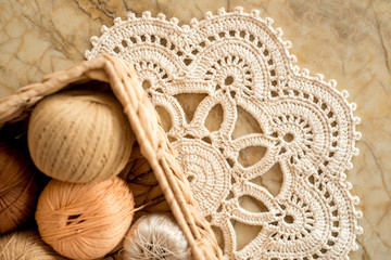 threads, crocheted round napkin. White napkin like a flower. on a marble light background. Balls of...