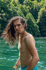 Obraz premium Young man with long hair standing waist in water