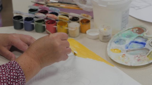 Artist draws a line of yellow paint on canvas paper, the artist in the Studio, the Creator makes a movement of the brush on the canvas. Concept of a work of art.