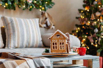 Christmas morning in the bright living room. Homemade gingerbread house on background room decorated for Christmas.