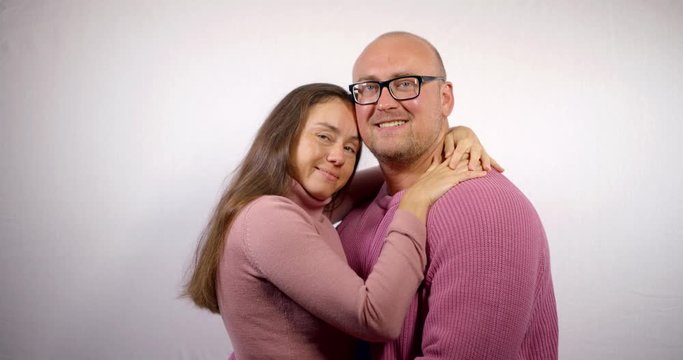 romantic couple in pink pullovers hugs and smiles slow