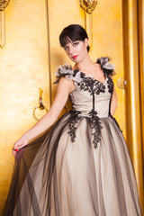 alluring sexy woman in evening dress posing over golden studio background