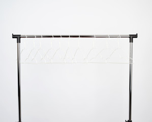 empty white metal hangers hang on a chrome bar