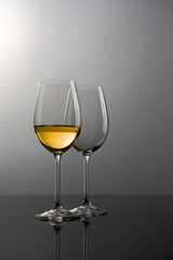 Two glasses of white wine against dark background.