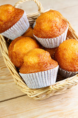 CLOSE UP OF MUFFIN IN WICKER BASKET ON WOODEN TABLE