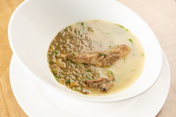 A bowl of homemade chili lentil soup with meat on wooden table. Restaurant menu