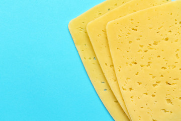 Slices of cheese on color background, top view