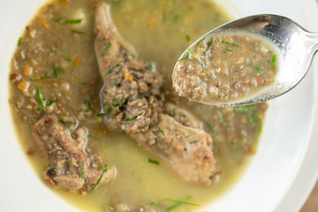 A bowl of homemade chili lentil soup with meat on wooden table. Restaurant menu