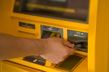 The person's hand is withdrawing from the ATM.