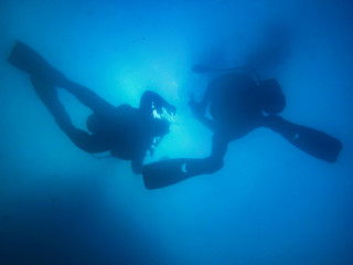 Two divers ascending to surface in hazy blue water