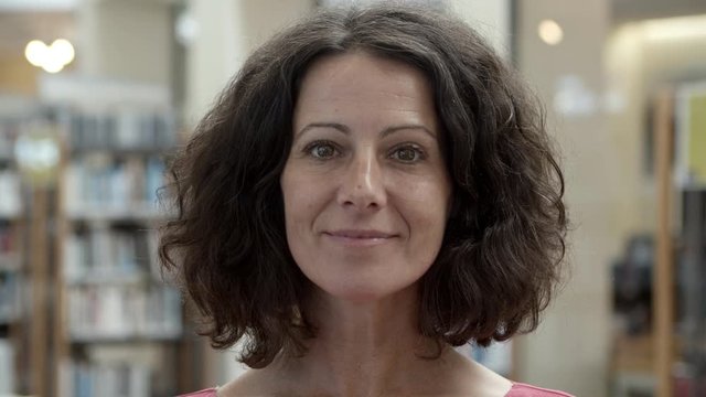 Cheerful middle aged Caucasian woman looking at camera. Front view of beautiful mature woman wearing pink blouse. Female beauty concept