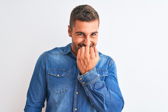 Young handsome man wearing denim jacket standing over isolated background looking stressed and nervous with hands on mouth biting nails. Anxiety problem.