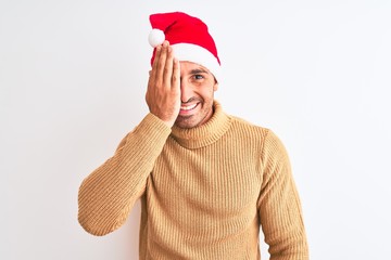 Young handsome man wearing christmas and turtleneck sweater over isolated background covering one eye with hand, confident smile on face and surprise emotion.