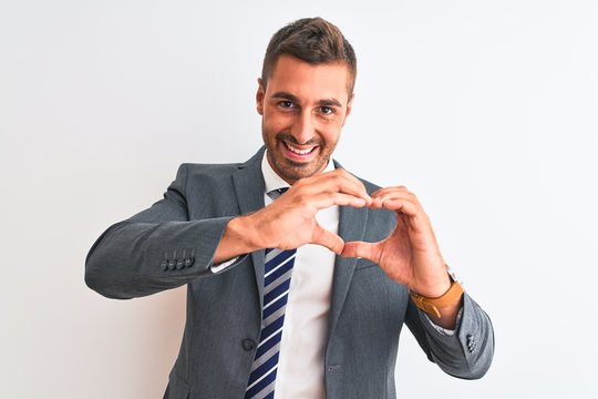 Young handsome business man wearing suit and tie over isolated background smiling in love doing heart symbol shape with hands. Romantic concept.