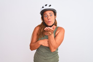 Middle age mature cyclist woman wearing safety helmet over isolated background looking at the camera blowing a kiss with hand on air being lovely and sexy. Love expression.