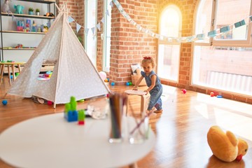 Beautiful caucasian infant playing with toys at colorful playroom. Happy and playful at kindergarten.