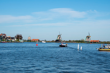 Obraz premium Zaanse Schans, Netherlands - 1 October 2019: Tourists sightseeng traditional Dutch rural houses in Zaanse Schans, is a typical small village within Amsterdam area.