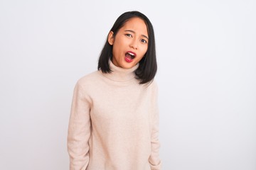 Young chinese woman wearing turtleneck sweater standing over isolated white background In shock face, looking skeptical and sarcastic, surprised with open mouth