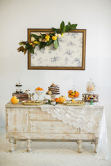 Sweet table. Halloween Wedding Luxor Decor. Chocolate cake with blackberries, blueberries, pears and cinnamon sticks. Cupcakes and tartlets with berries. Surrounded by orange pumpkins