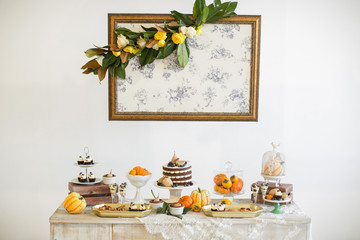 Sweet table. Halloween Wedding Luxor Decor. Chocolate cake with blackberries, blueberries, pears and cinnamon sticks. Cupcakes and tartlets with berries. Surrounded by orange pumpkins