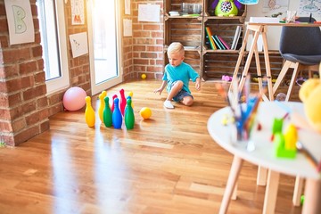 Young caucasian kid playing at kindergarten with toys. Preschooler boy happy at playroom.